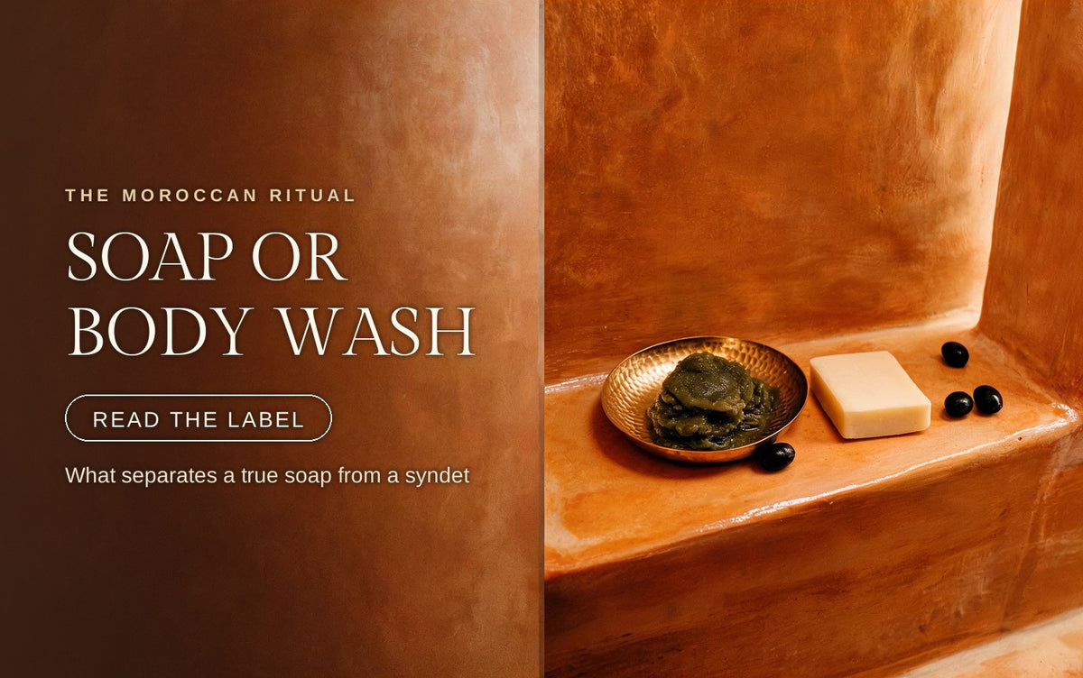 Soft olive-green beldi soap paste in a brass dish next to a plain cream soap bar and cured black olives on tadelakt