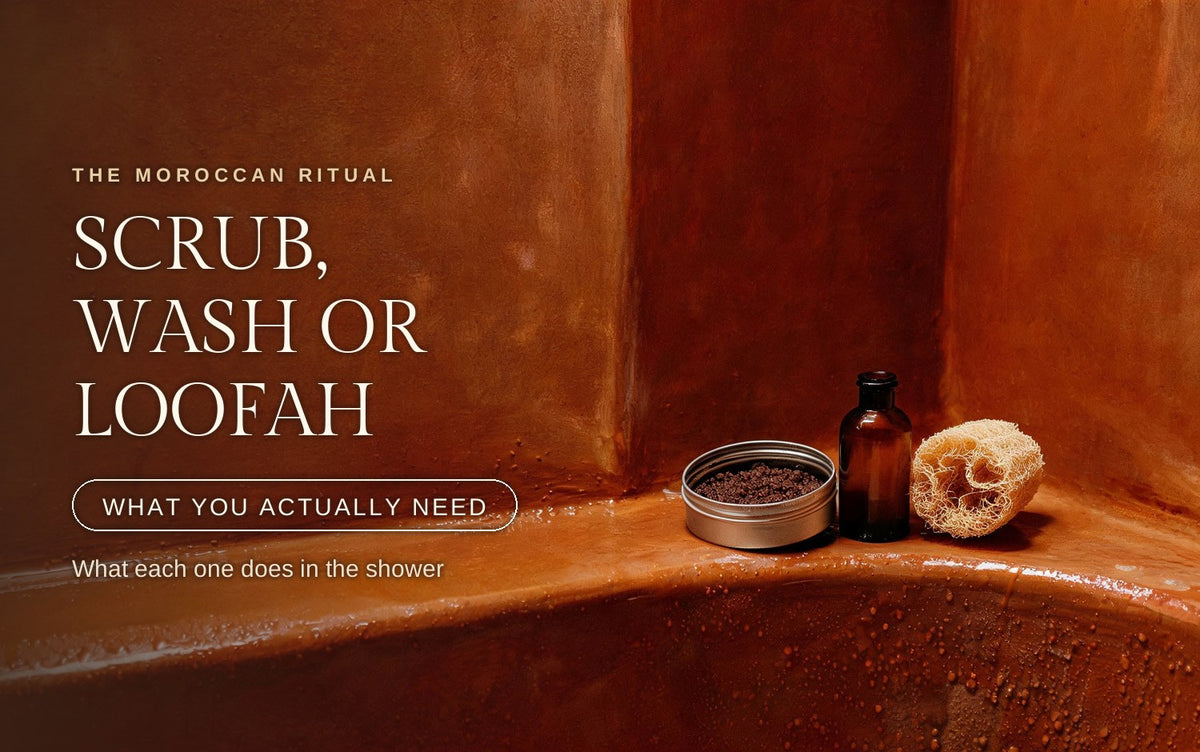 An open metal tin of dark coarse-grained body scrub, a plain amber glass bottle and a dried loofah sponge standing side by side on a wet terracotta ledge in a warm hammam corner, water beaded across the clay below