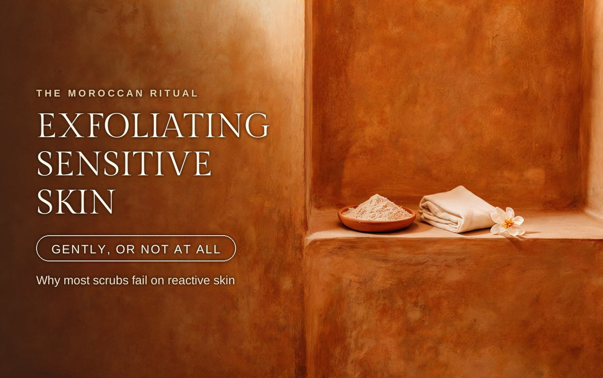A shallow terracotta dish heaped with finely milled pale scrub powder, a folded cream muslin cloth and a single pale blossom resting on a warm tadelakt clay ledge in soft diffused light