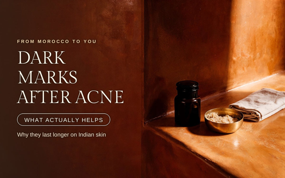 Dark glass apothecary jar and a brass bowl of pale scrub beside folded linen on a sunlit clay ledge